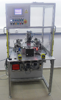 Jednoúčelový stroj určený pro montáž vystřihaných tvarových kontaktů do plastového dílce. Základem stroje je šestipolohový otočný stůl osazený jednotlivými přípravky a technologiemi.